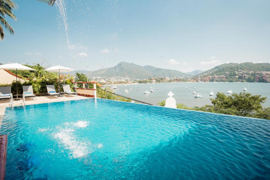 een groot zwembad met uitzicht op het water bij Villa del Pescador in Zihuatanejo