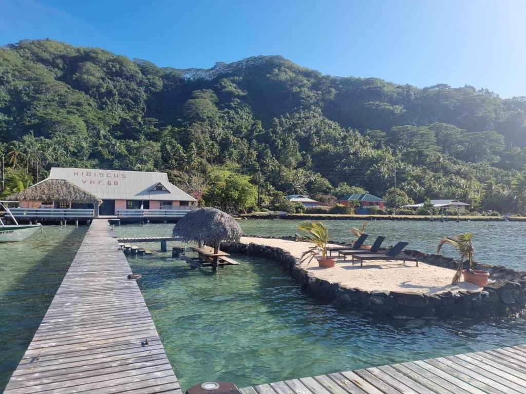 a dock with chairs and a building in the water at Pension Hibiscus Taha'a in Vaitoare
