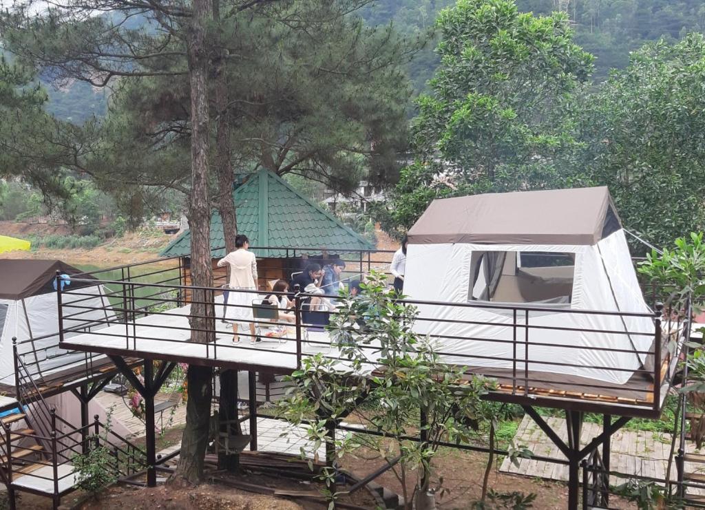 une cabane dans les arbres avec des personnes debout sur une terrasse dans l'établissement Lều biệt thự, à Hanoï