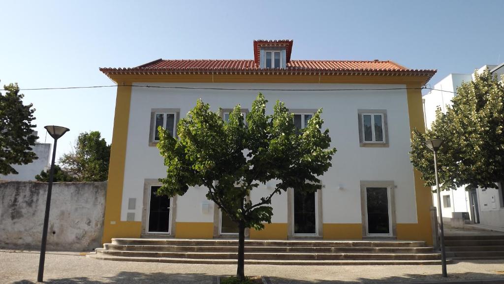 una casa blanca y amarilla con un árbol delante en Sonetos do Tejo, en Vila Nova da Barquinha