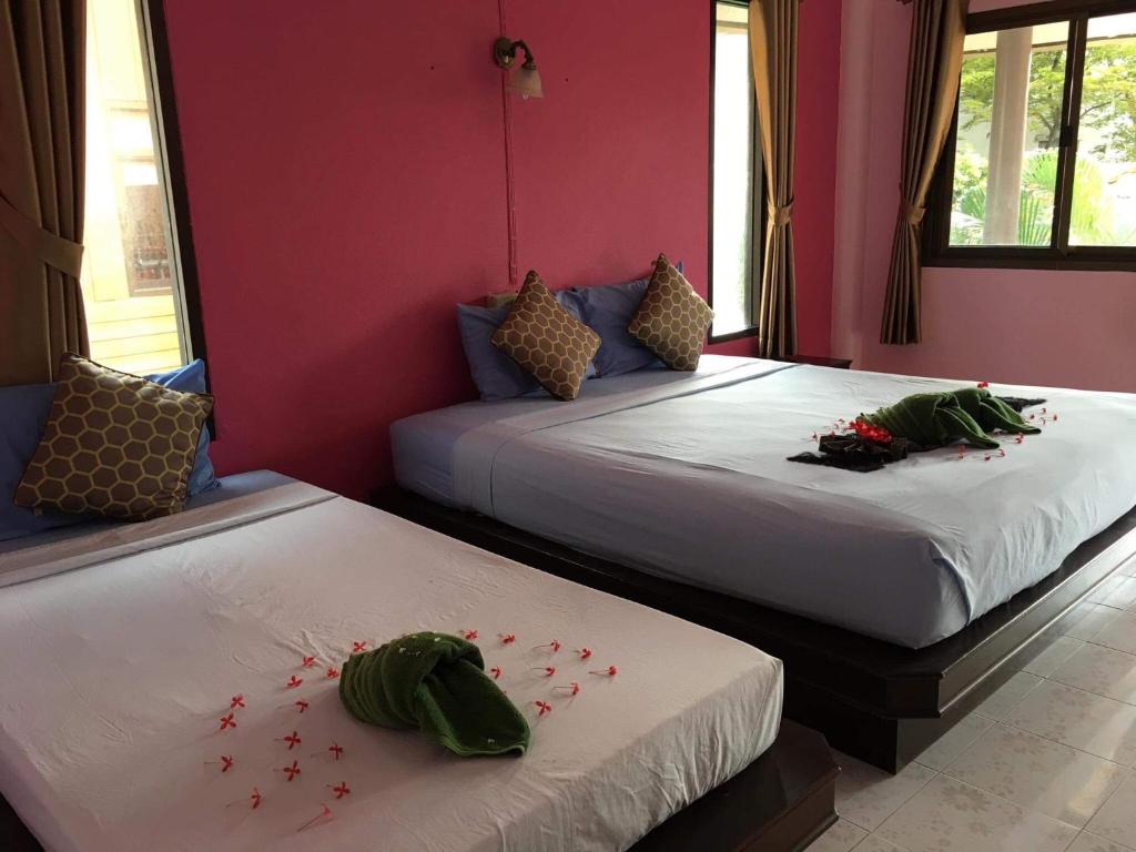 two beds in a room with red walls at Lanta Garden Home in Ko Lanta