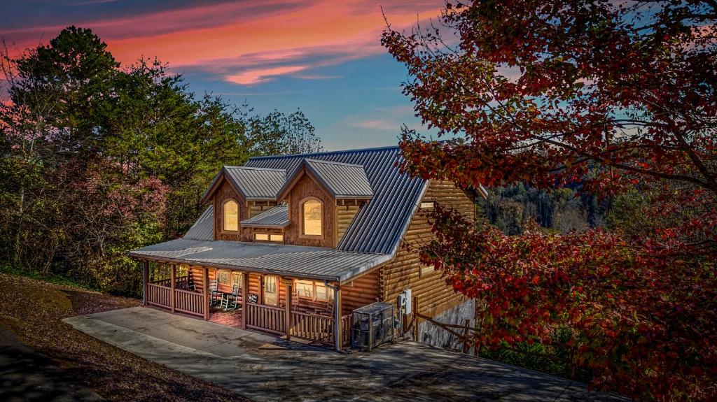 ein Holzhaus mit einem Metalldach oben in der Unterkunft Bearfoot Pines - True Log Cabin - Wi-Fi, Hot Tub, Fishing, Deck with views! - Mins to PF in Sevierville