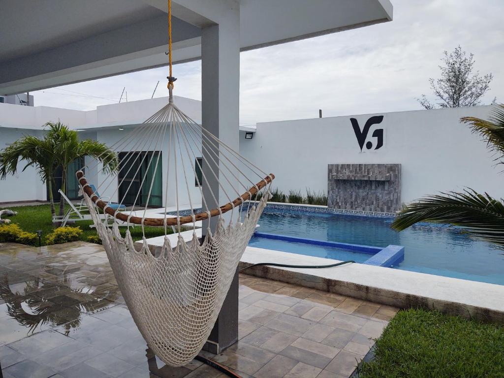 a hammock hanging from a house with a swimming pool at V&G Las vacaciones que mereces in Ursulo Galván