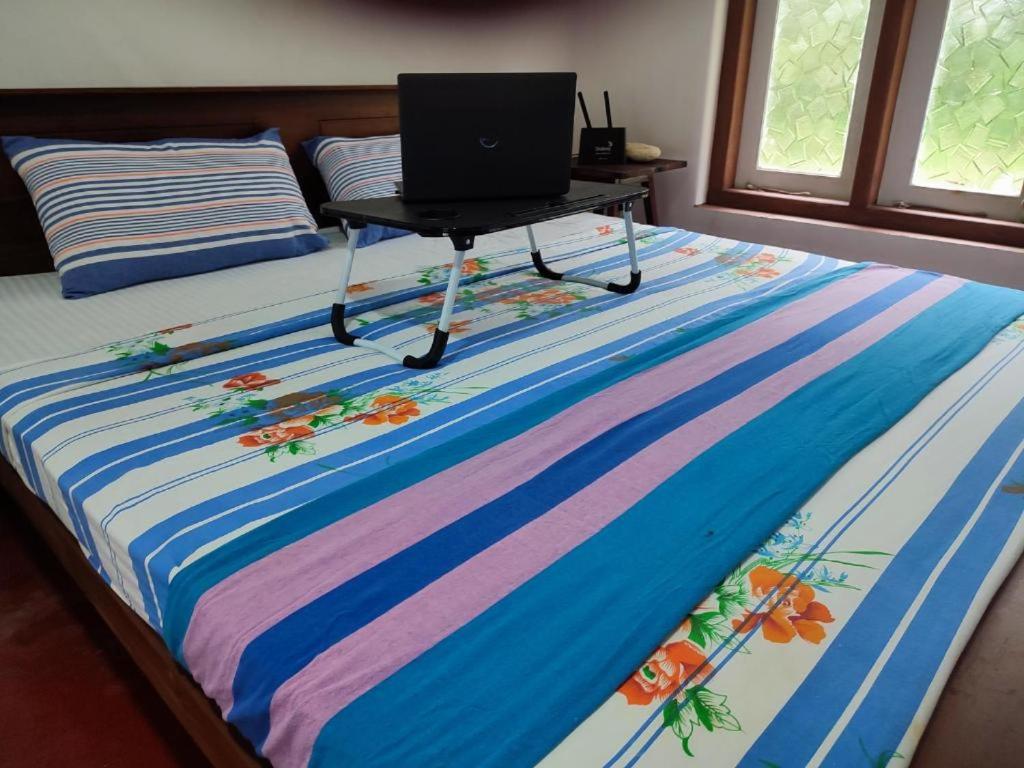 a bed with a laptop on a table on it at The Duke in Weligama