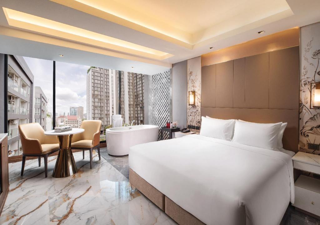 SAMALA Hotel Bangkok في بانكوك: غرفة الفندق بسرير كبير وحوض استحمام