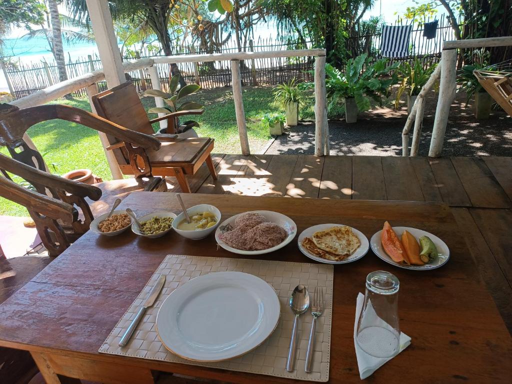 a wooden table with plates of food on it at Beach House Kalukatiya - Family Villa, Seaview Room, Garden Room in Dickwella