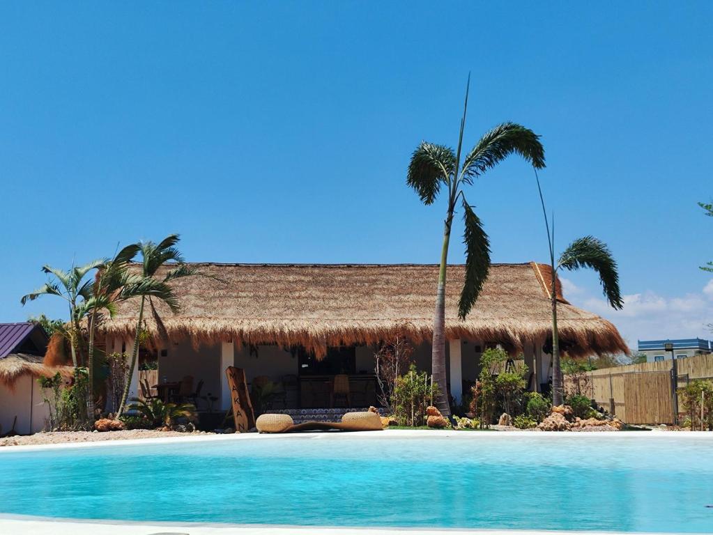 uma casa com uma palmeira e uma piscina em Solimar Seaside Cabanas em Tambobong