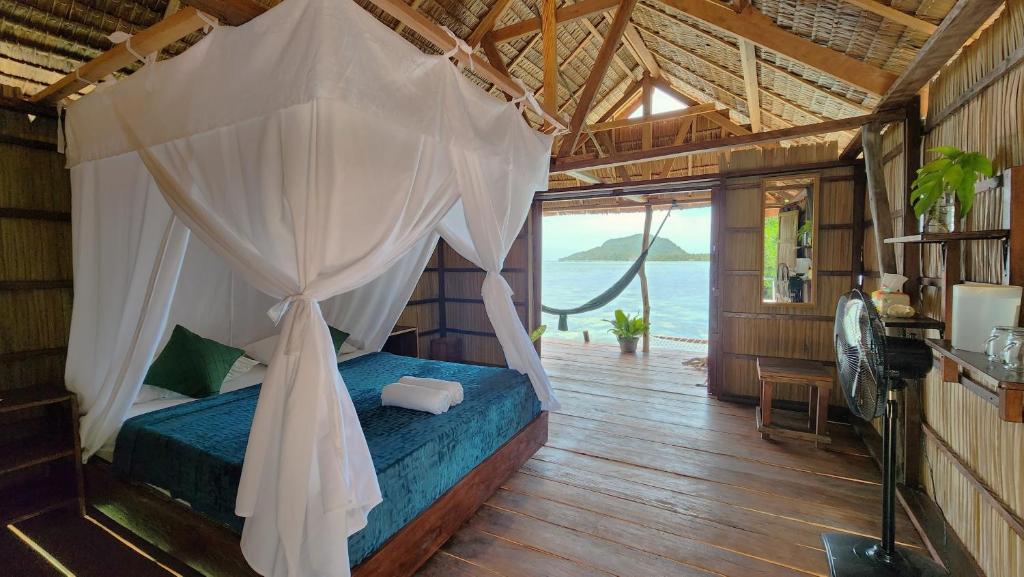 a bedroom with a bed with a mosquito net at Mansuar Raja Ampat Bungalows in Kri