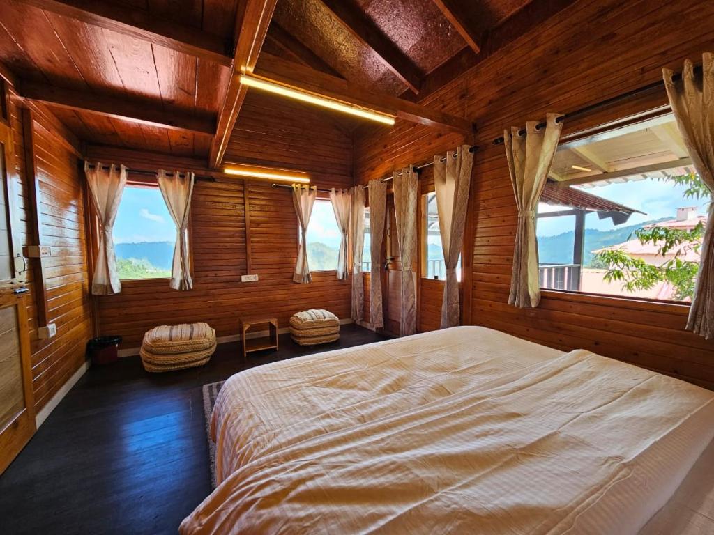 ein Schlafzimmer mit einem großen Bett in einem Zimmer mit Fenstern in der Unterkunft Himalayan Havenwood in Mukteswar