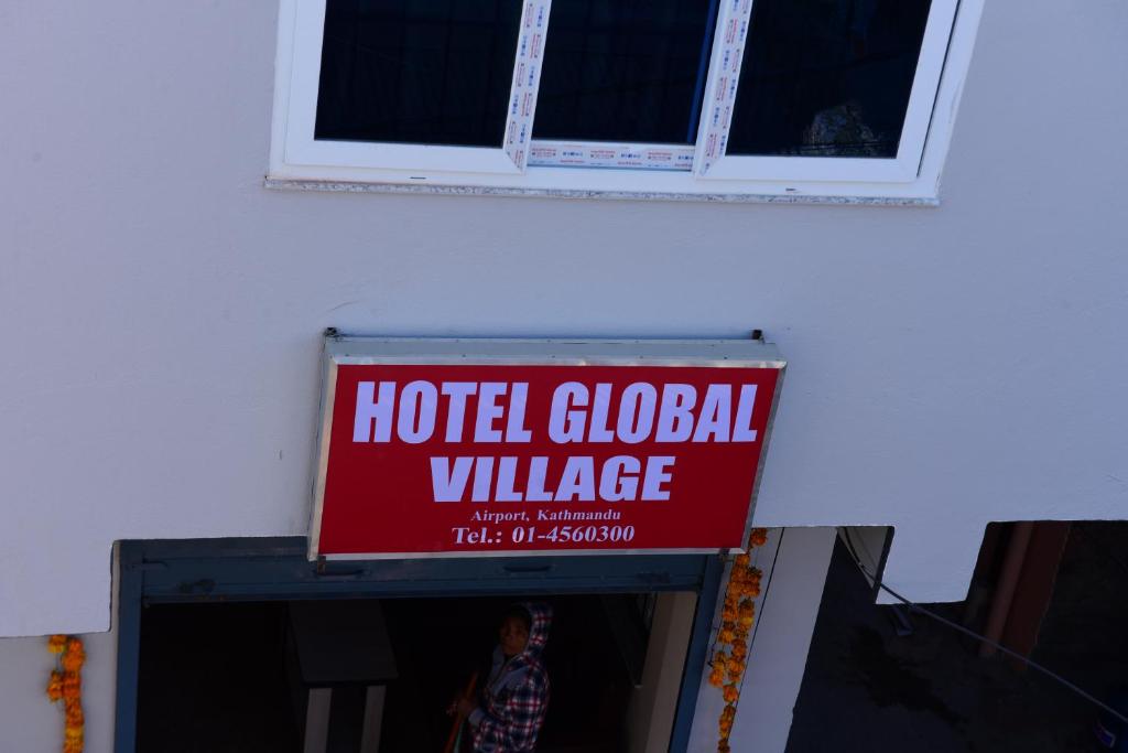 ein globales Dorfschild an der Seite eines Gebäudes in der Unterkunft Hotel Global Village in Kathmandu