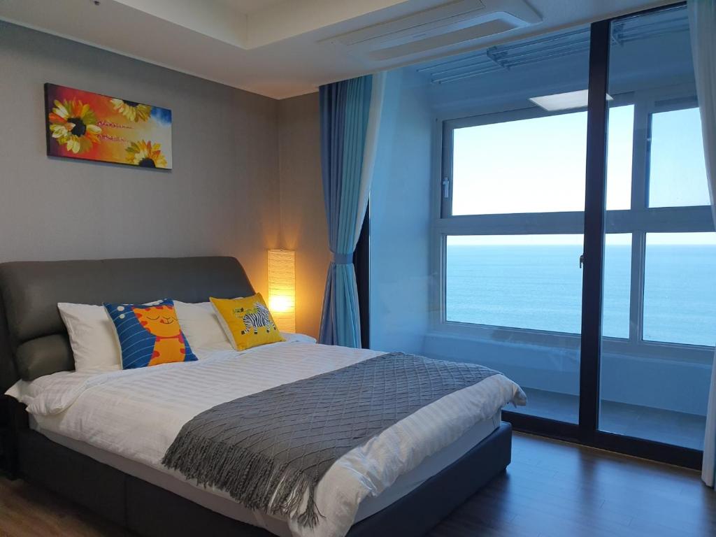 a bedroom with a bed and a large window at Eastern View Premium Residence in Ulsan