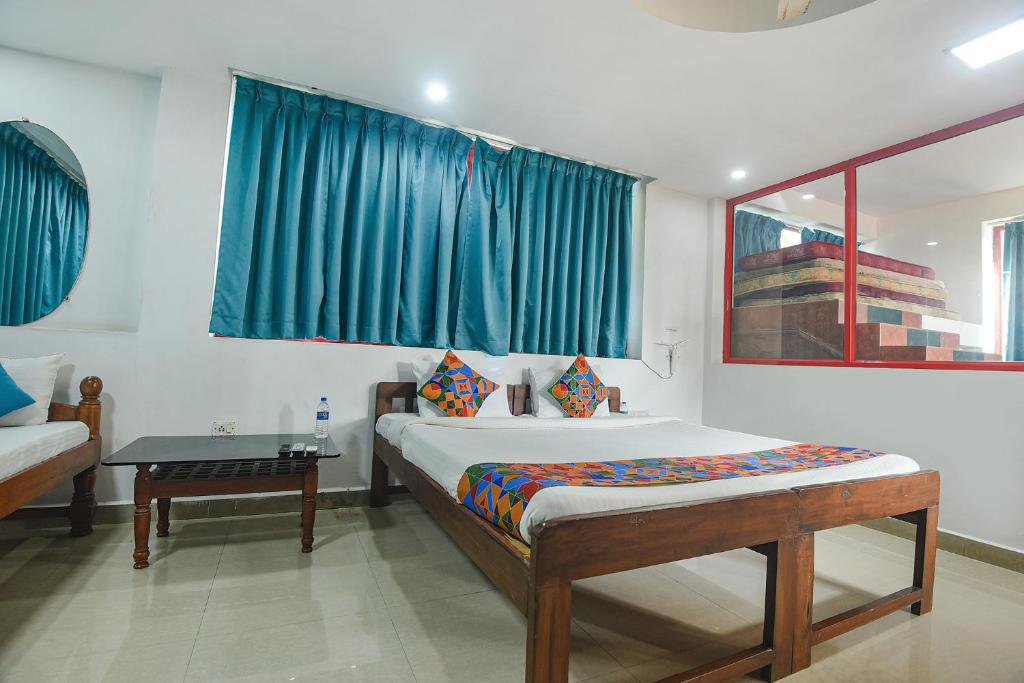 a bedroom with a bed with blue curtains and a table at FabExpress Stargaze Beach in Anjuna