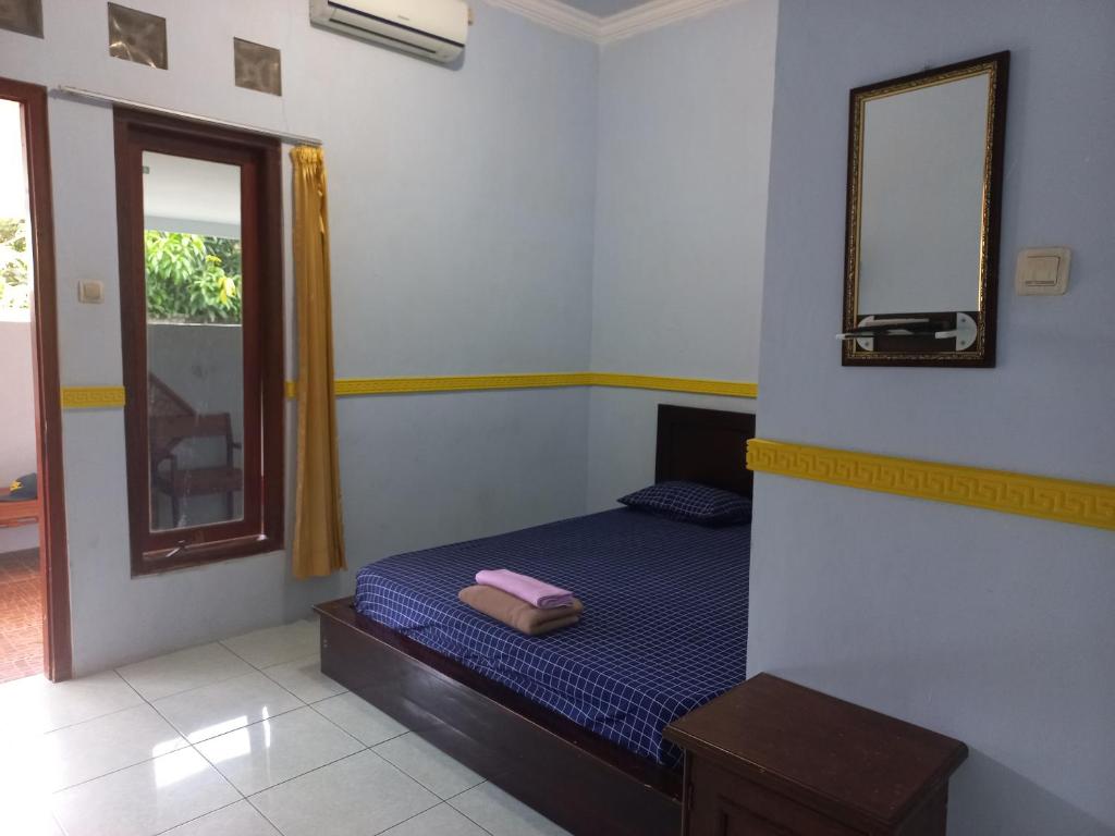 a small bedroom with a bed and a mirror at Homestay 77 Borobudur in Borobudur