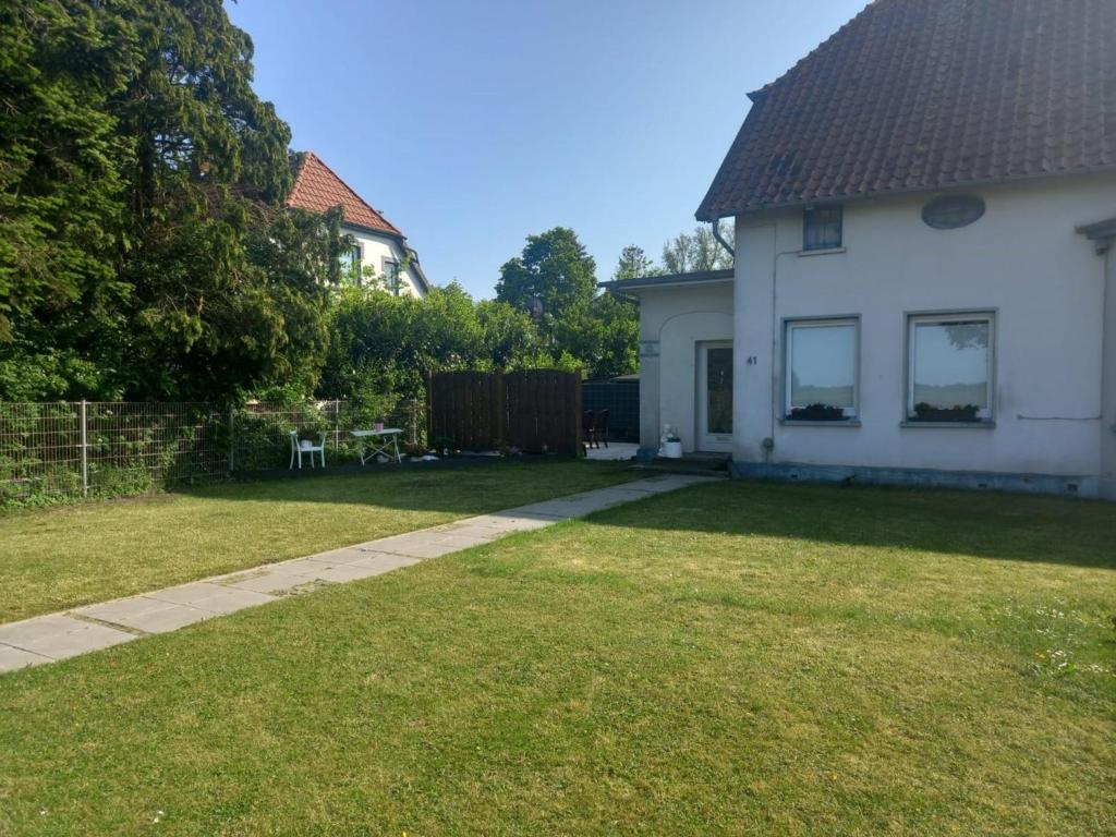a yard with a white house and a fence at Ferienwohnung Landliebe in Süderschweiburg