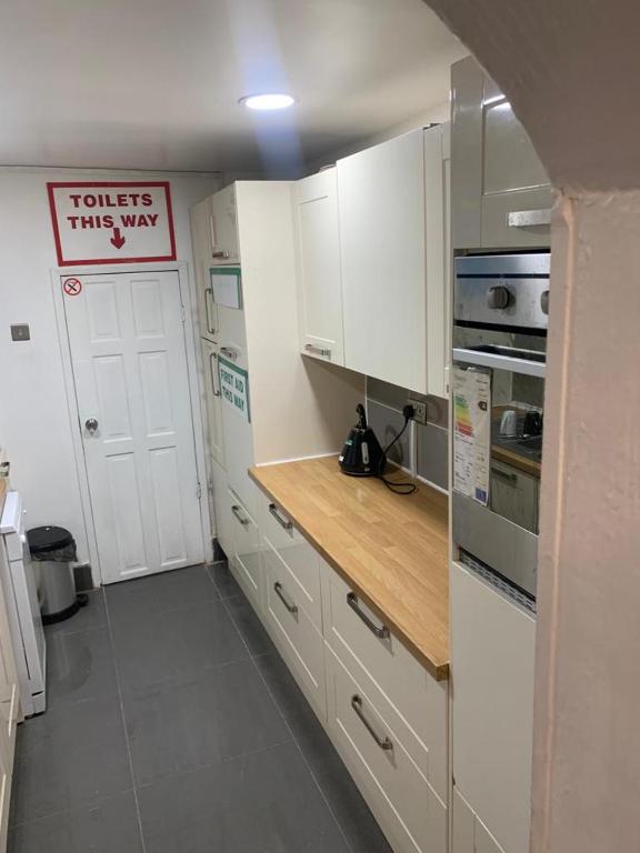 a kitchen with white cabinets and a sign that reads toilets this way at Gordon Road in Gillingham