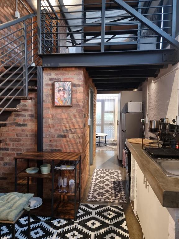 a kitchen with a staircase and a brick wall at CM Loft Maboneng in Johannesburg
