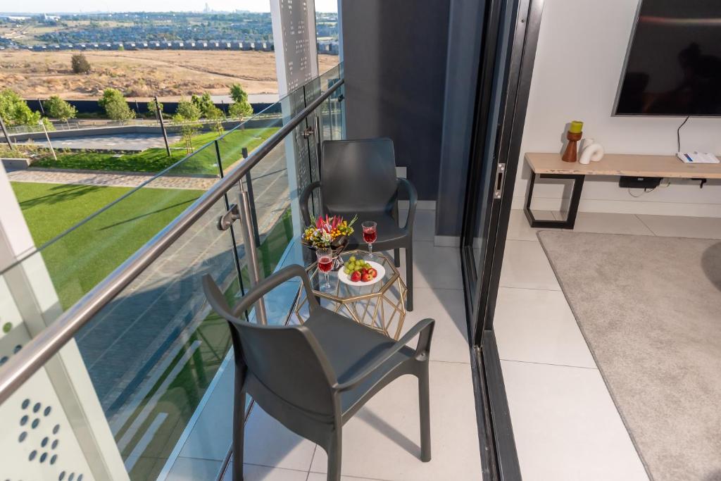 einen Balkon mit 2 Stühlen und einem Tisch in der Unterkunft Executive apartment, Ellipse in Midrand