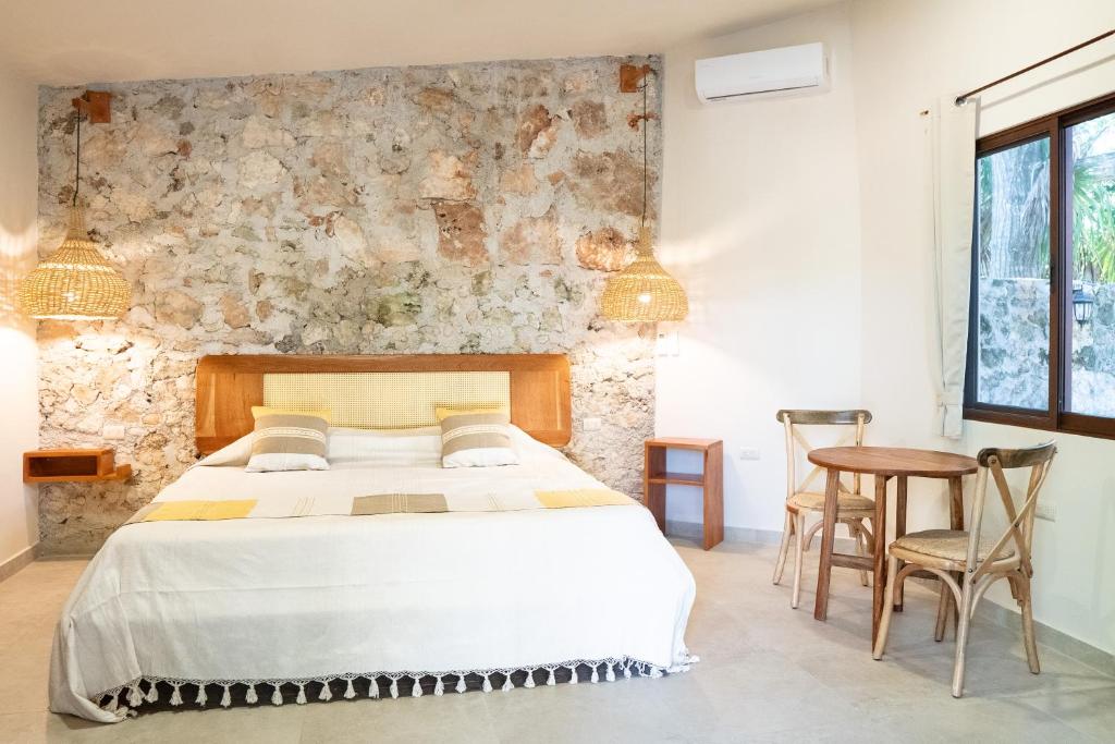 a bedroom with a bed and a stone wall at Casa Cactus Buenavista in Bacalar