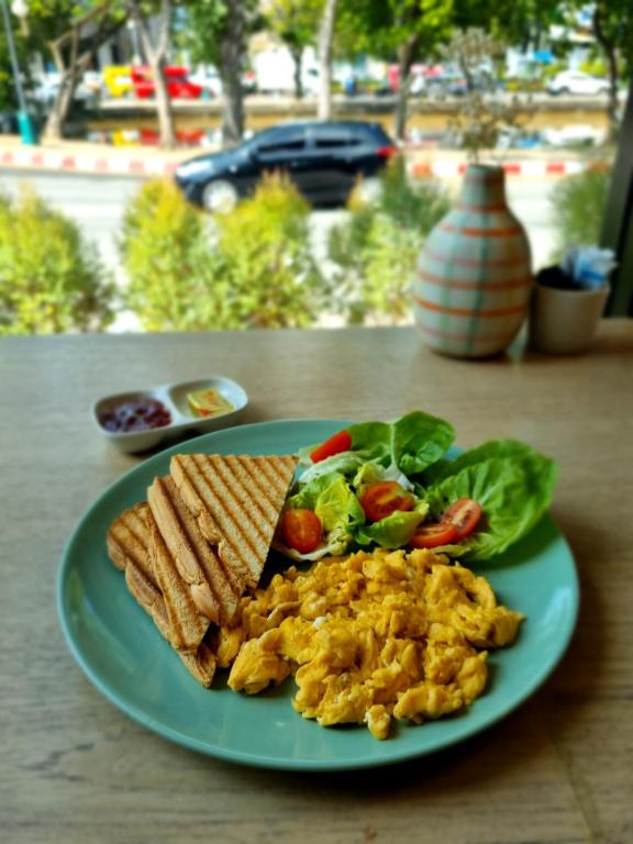 Scrambled eggs, toast and salad served on a green plate.