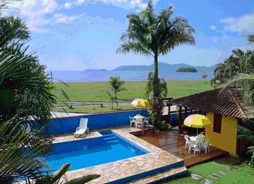 een zwembad met stoelen en parasols naast een huis bij Pousada Vistamar in Paraty