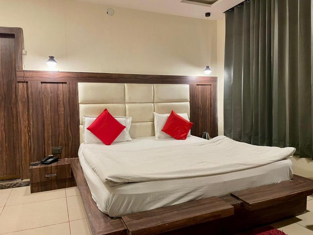 a bedroom with a large bed with two red pillows at Hotel Himgiri Pakki Daki in Jammu