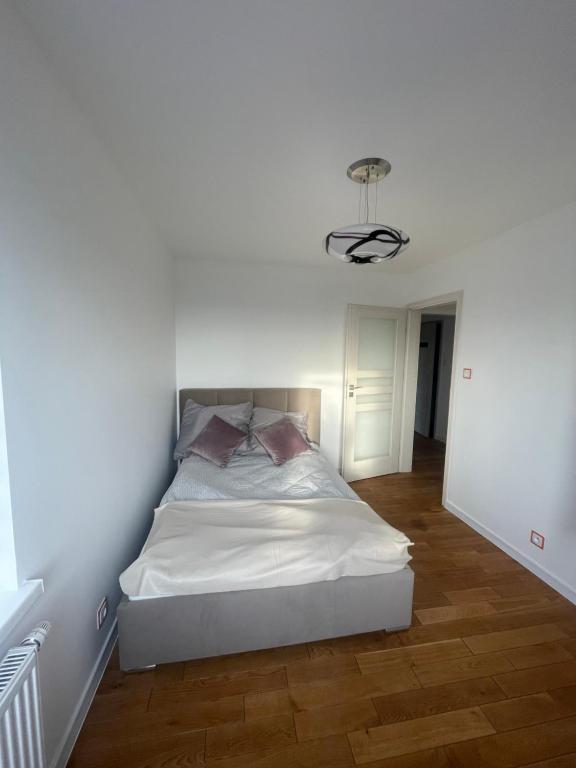 a white bedroom with a bed in a room at Apartament Szczytno II in Szczytno