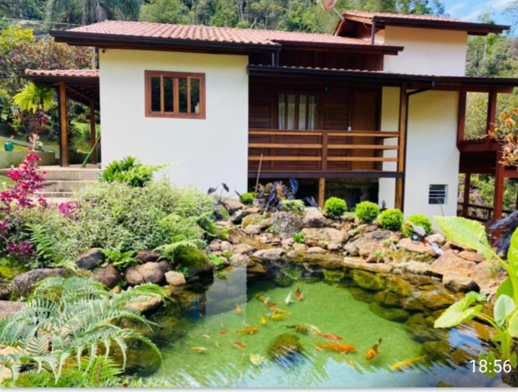 une maison avec un étang de carpes koï en face d'une maison dans l'établissement Lindo Sítio Em Domingos Martins, à Domingos Martins