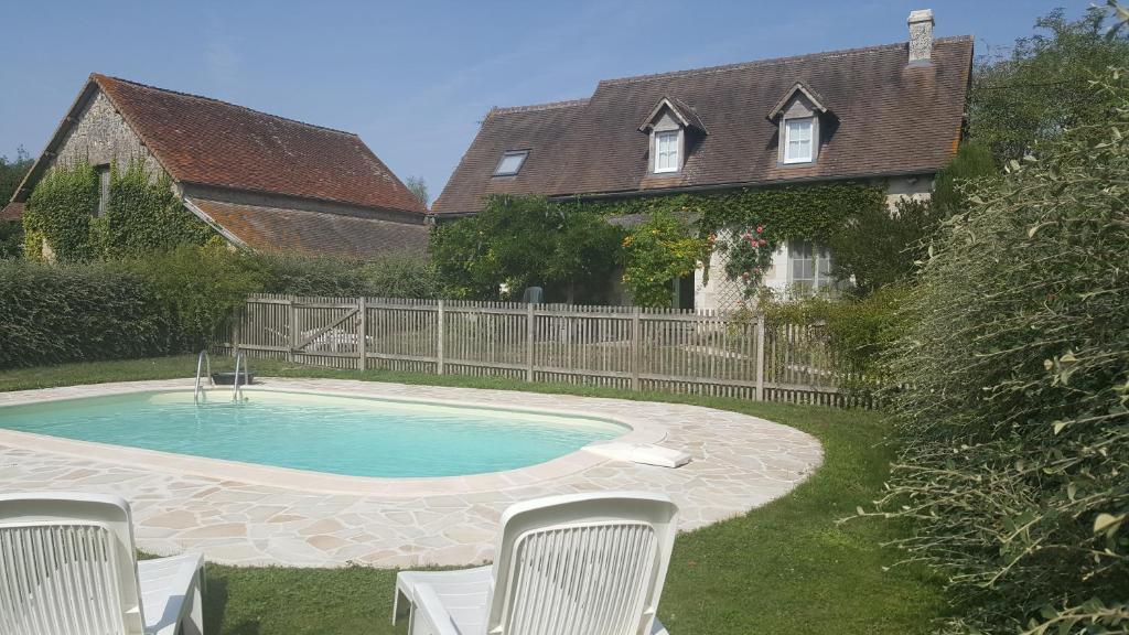 uma piscina com cadeiras num quintal em LE GÎTE DU VIGNERON em Sennevières