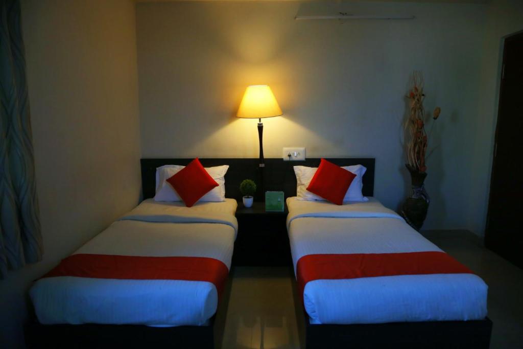 two beds in a hotel room with a lamp at Orange Corner Hotel, MONTHLY STAY AVAILABLE in Yelahanka