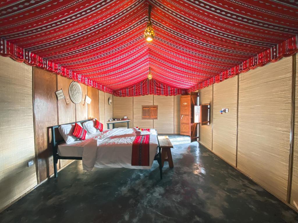 a bedroom with a bed with a red ceiling at SAMA Al Areesh Camp in Al Qābil