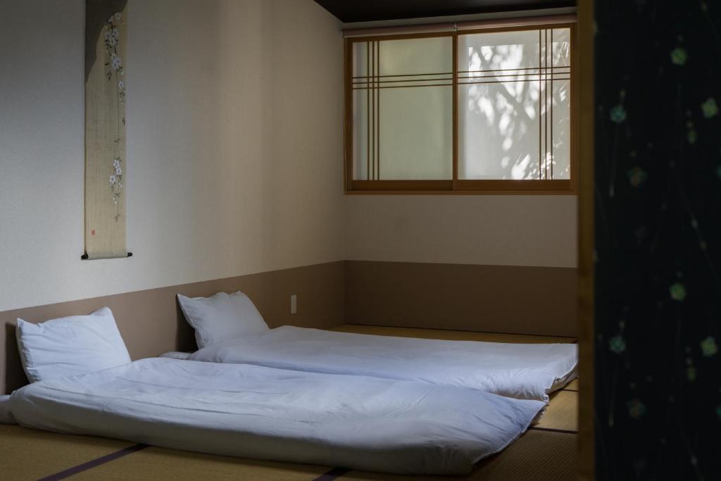 a bedroom with two beds and a window at Guesthouse ZenNichi in Kyoto