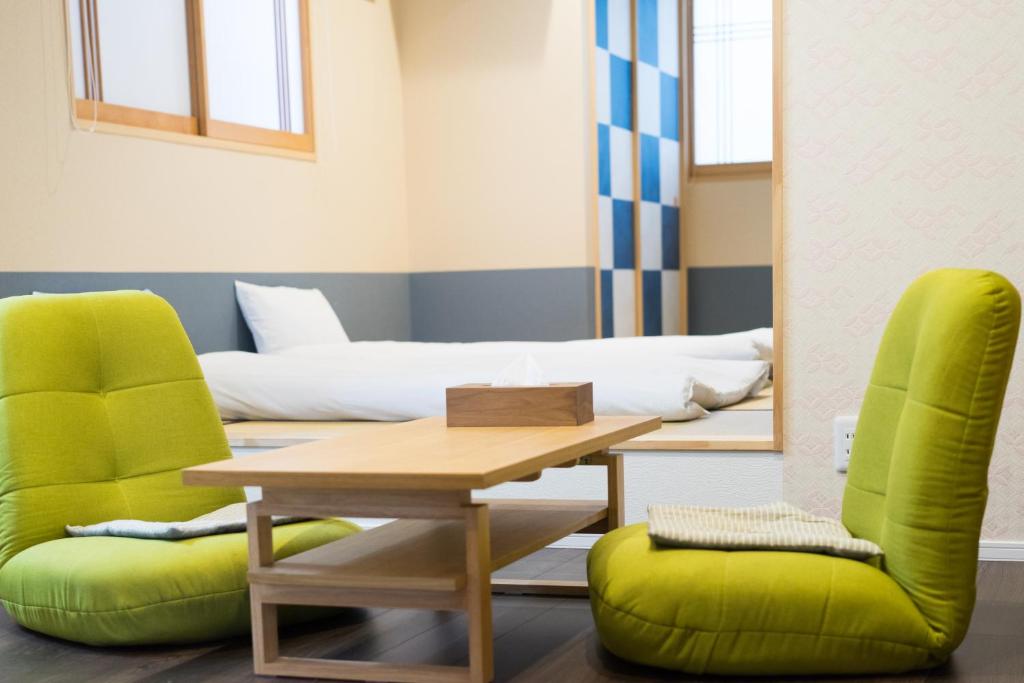 a room with a table and two green chairs at Guesthouse ZenNichi in Kyoto