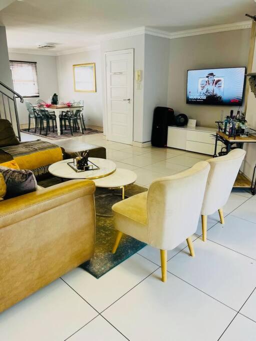 a living room with a couch and chairs and a tv at musgrave manors villa in Durban