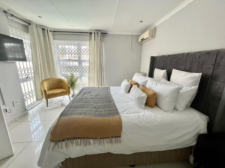 a bedroom with a large bed with white pillows at musgrave manors villa in Durban