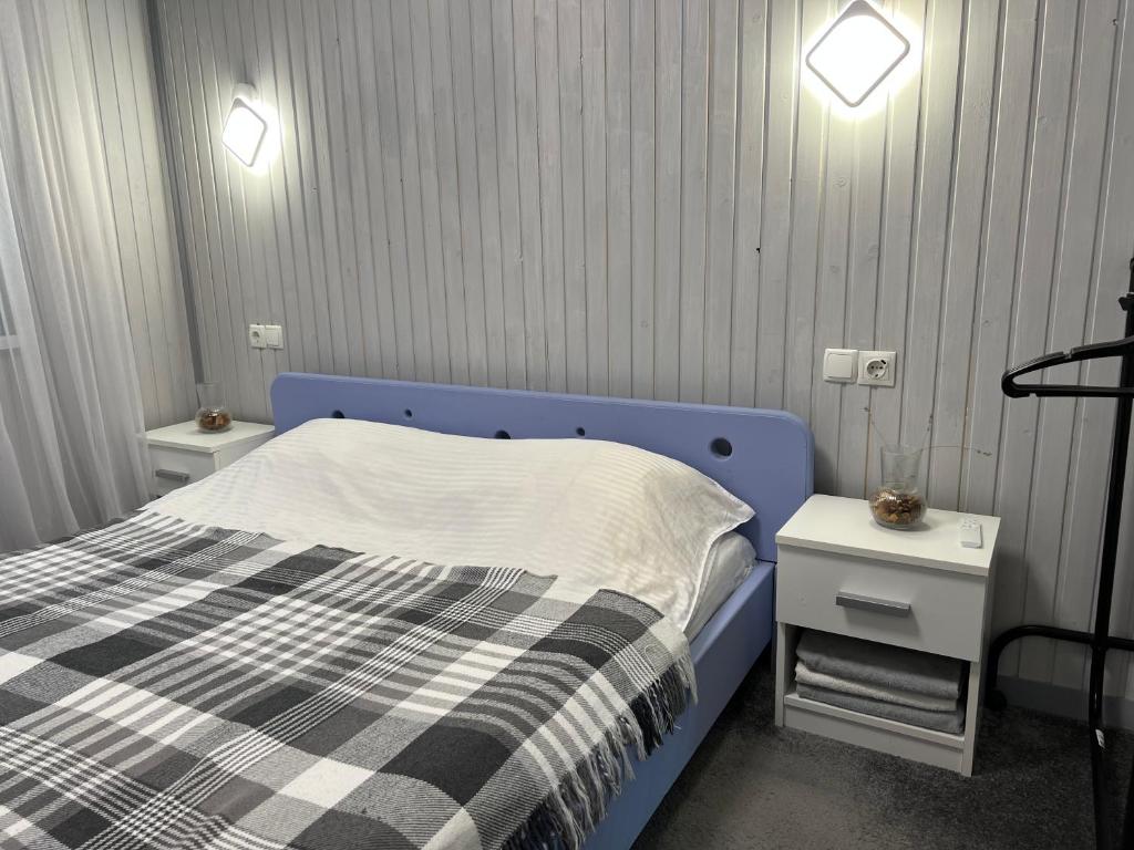 ein Schlafzimmer mit einem blauen Bett und zwei Nachttischen in der Unterkunft Sonna in Podzakharychi