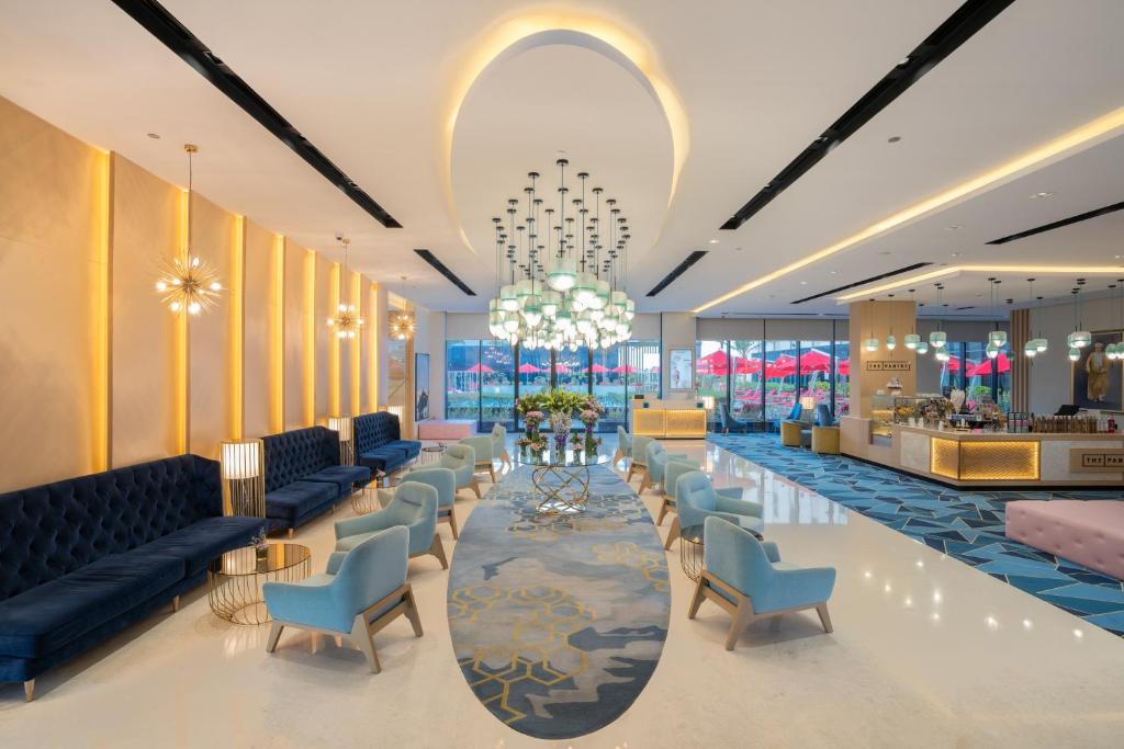 een lobby met banken en stoelen en een kroonluchter bij Maani Muscat Hotel & Suites in Muscat