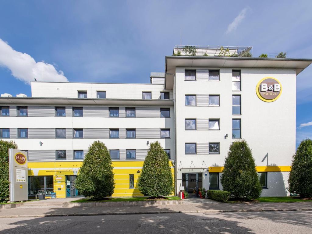 een groot wit gebouw met een bergbord erop bij B&B Hotel München City-Nord in München