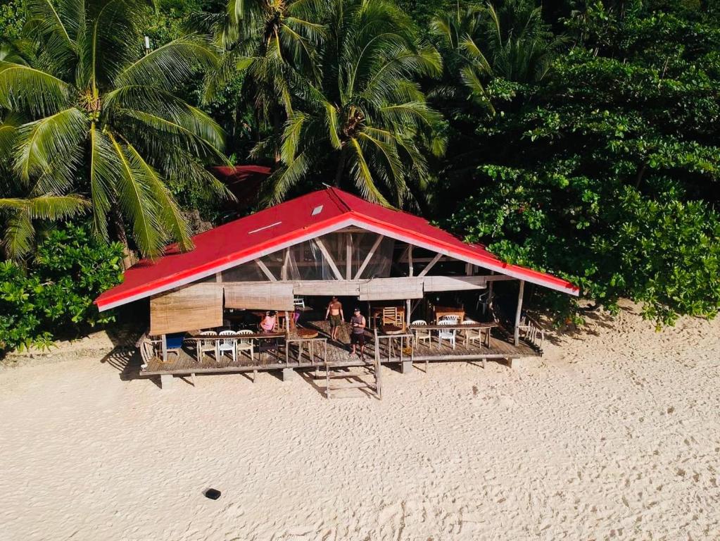 a restaurant with a red roof on a beach at White Beach Front and Cottages in Buruanga