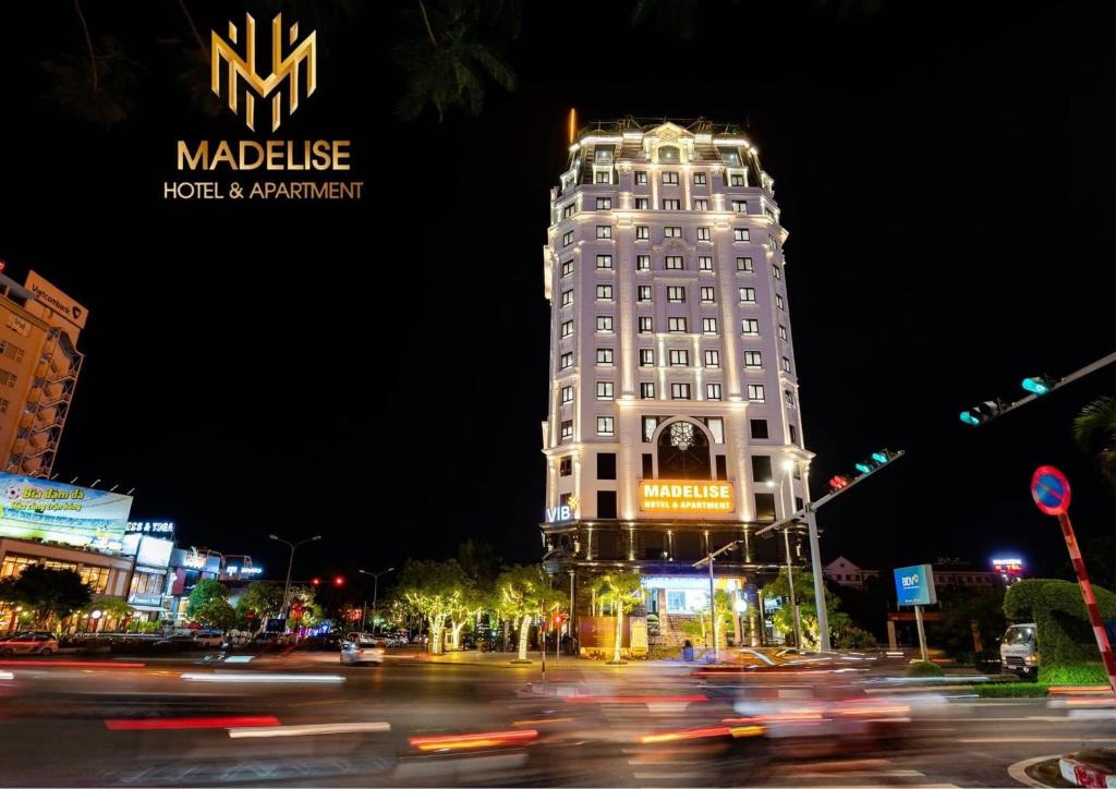 un edificio blanco alto con un cartel en él por la noche en MADELISE HOTEL&APARTMENT, en Hai Phong