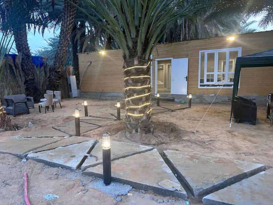 a palm tree with candles in front of a house at كوخ ريفي داخل مزرعه in Madain Saleh