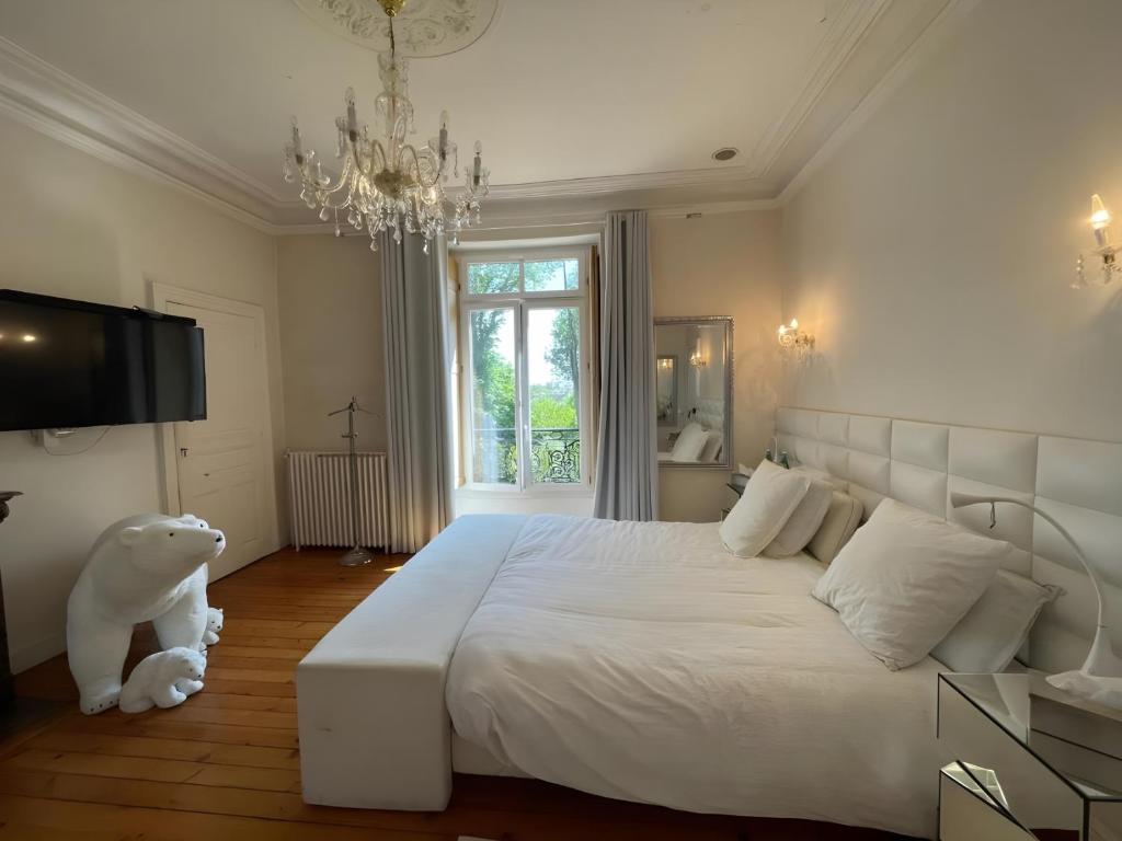 a bedroom with a large white bed and a chandelier at Domaine de la Belvaudière - luxueux - 24H du Mans - 20p - Rêve au Mans in Saint Pavace