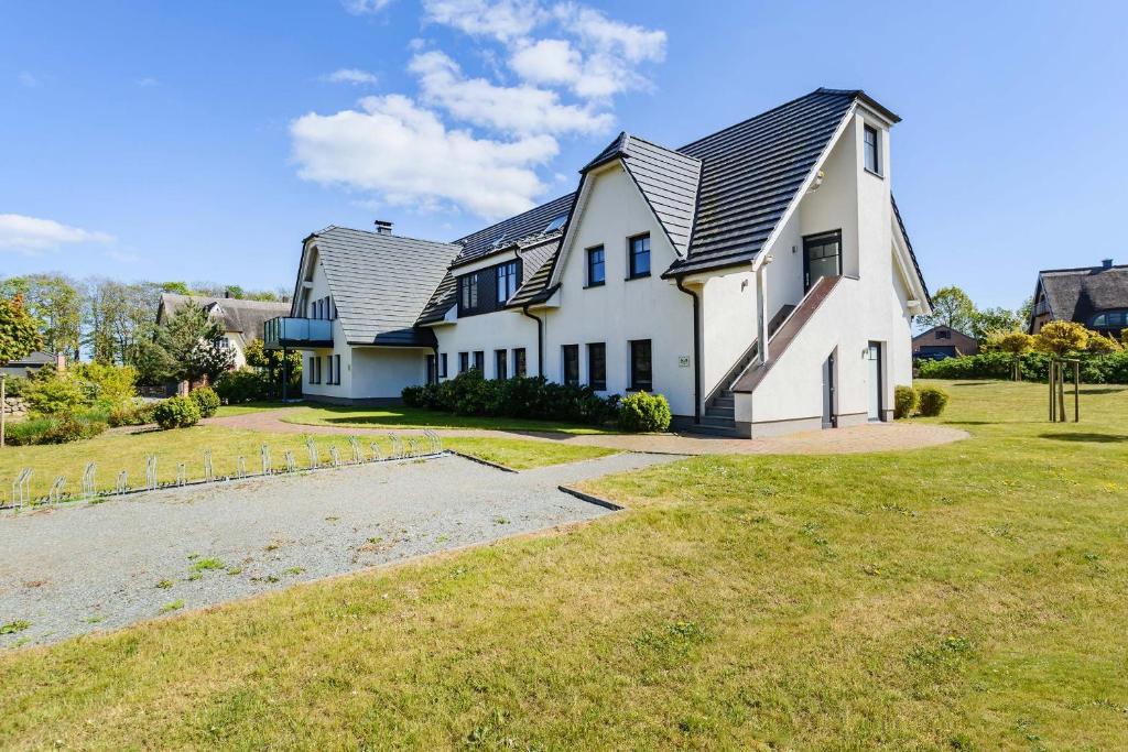 ein großes weißes Haus mit einem Walmdach in der Unterkunft Mönchgut - Strand Resort Rex Rugia App 05 in Lobbe