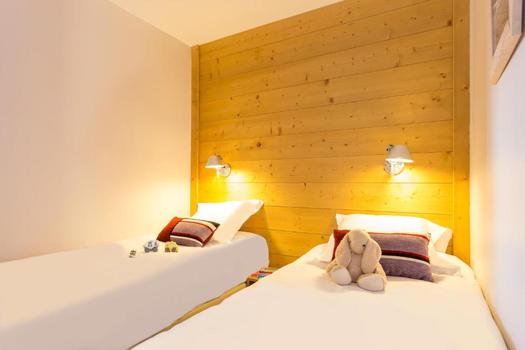 two beds in a room with wooden walls at Résidence Pierre &amp; Vacances Les Néréides in Belle Plagne