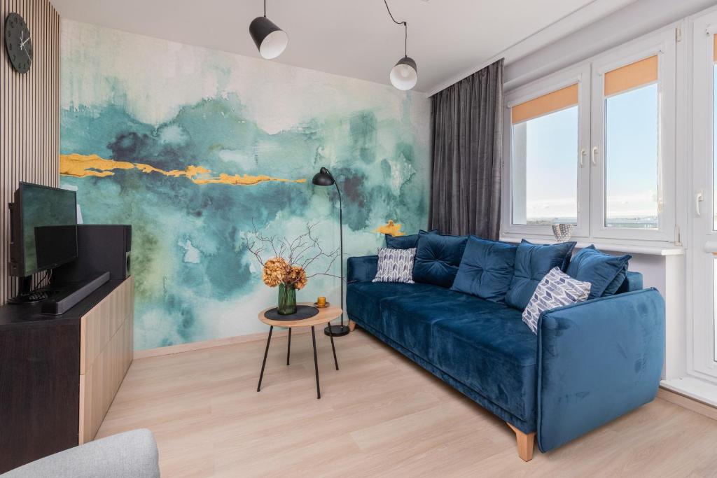 a blue couch in a living room with a painting at Cozy Pastel Studio in Gdańsk by Renters in Gdańsk
