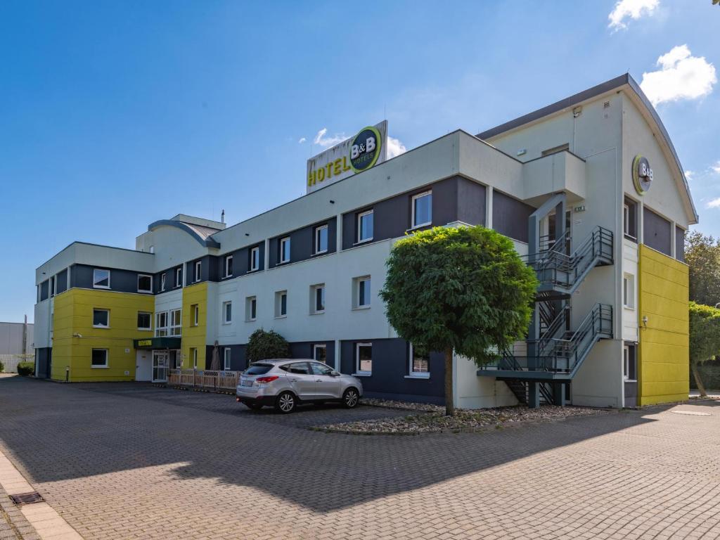 ein Gebäude mit einem davor geparkt in der Unterkunft B&B HOTEL Aachen-Würselen in Würselen