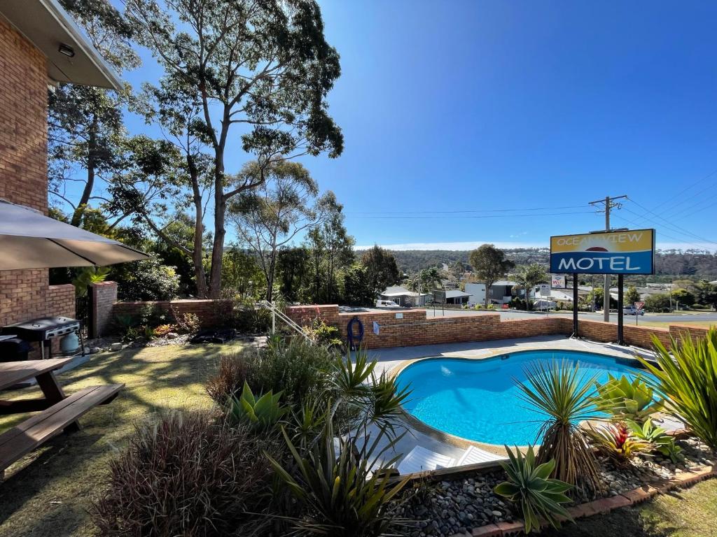 a swimming pool in a yard with a motel sign at Ocean View Motor Inn Merimbula in Merimbula