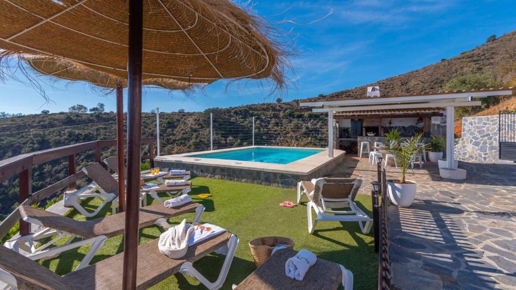uma villa com uma piscina com cadeiras e um guarda-sol em Cortijo La Envarra El Borge by Ruralidays em Moclinejo