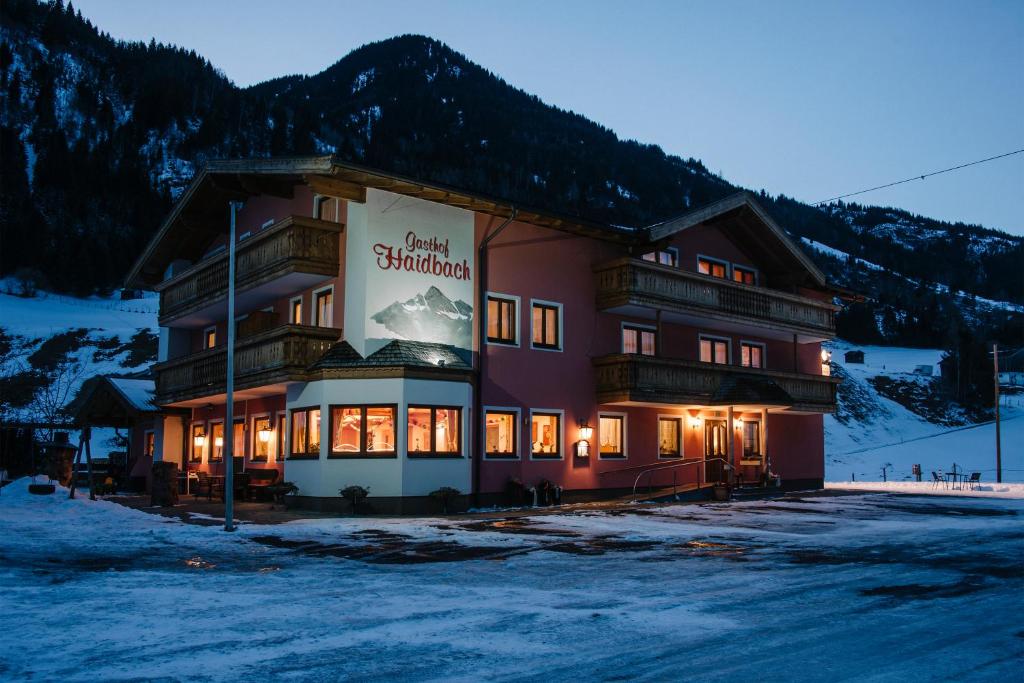 un gran edificio con un cartel en la nieve en Gasthof Haidbach, en Mittersill