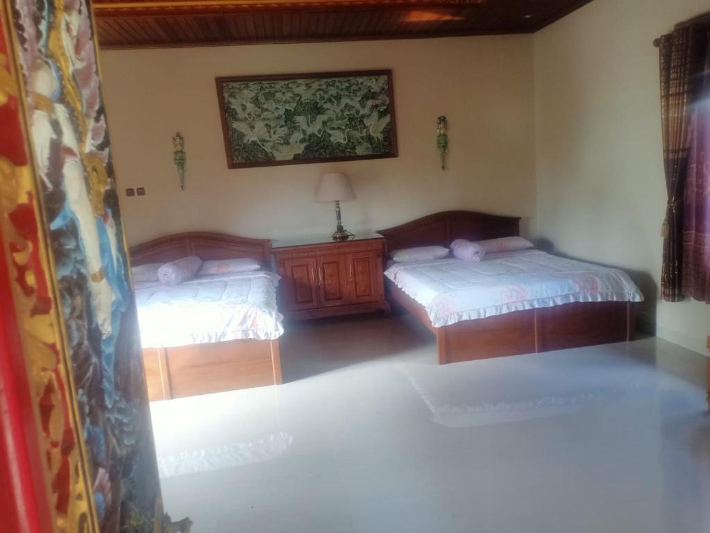 a bedroom with two beds and a painting on the wall at Puri Agung Inn in Sidemen