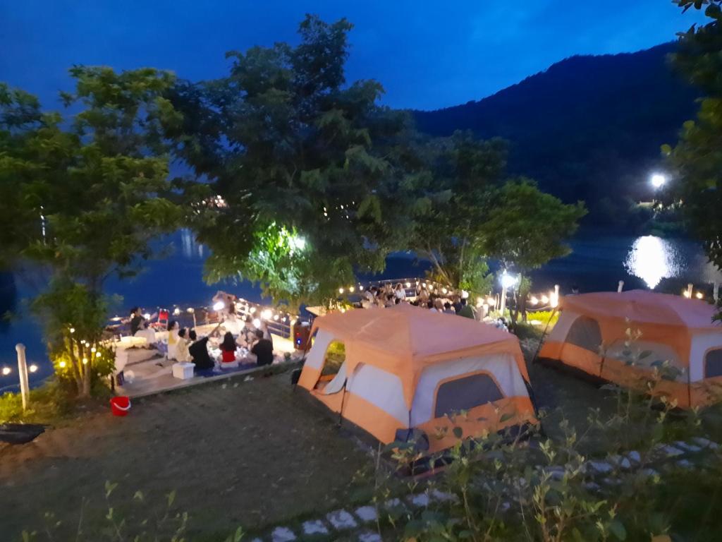 um grupo de tendas estacionadas ao lado de um lago à noite em Nhà trên cây em Hanói